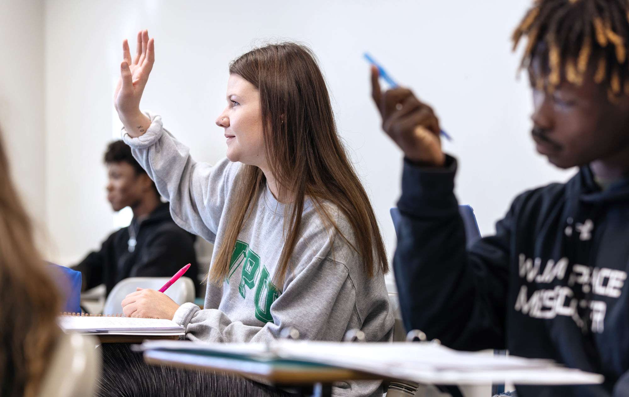 A Peace student raises her hand during class.